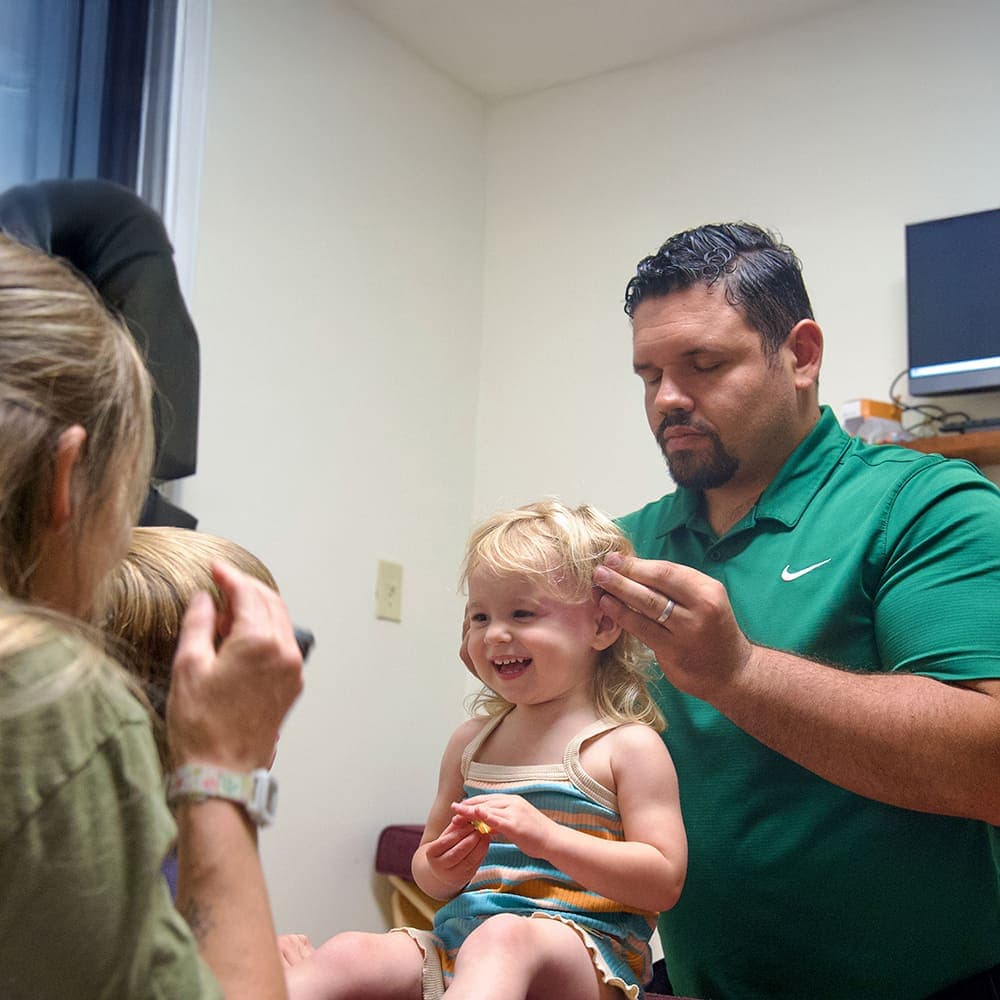 Dr. Vin gently adjusting a smiling toddler at Sláinte Chiropractic