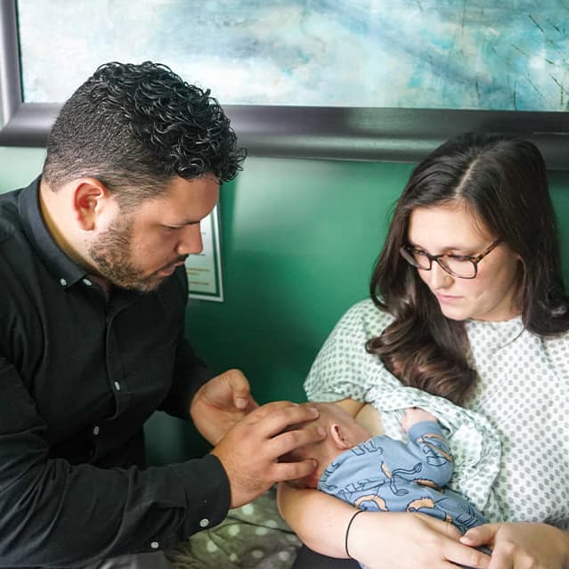 Dr. Vin caring for a baby in mom's arms at Sláinte Chiropractic