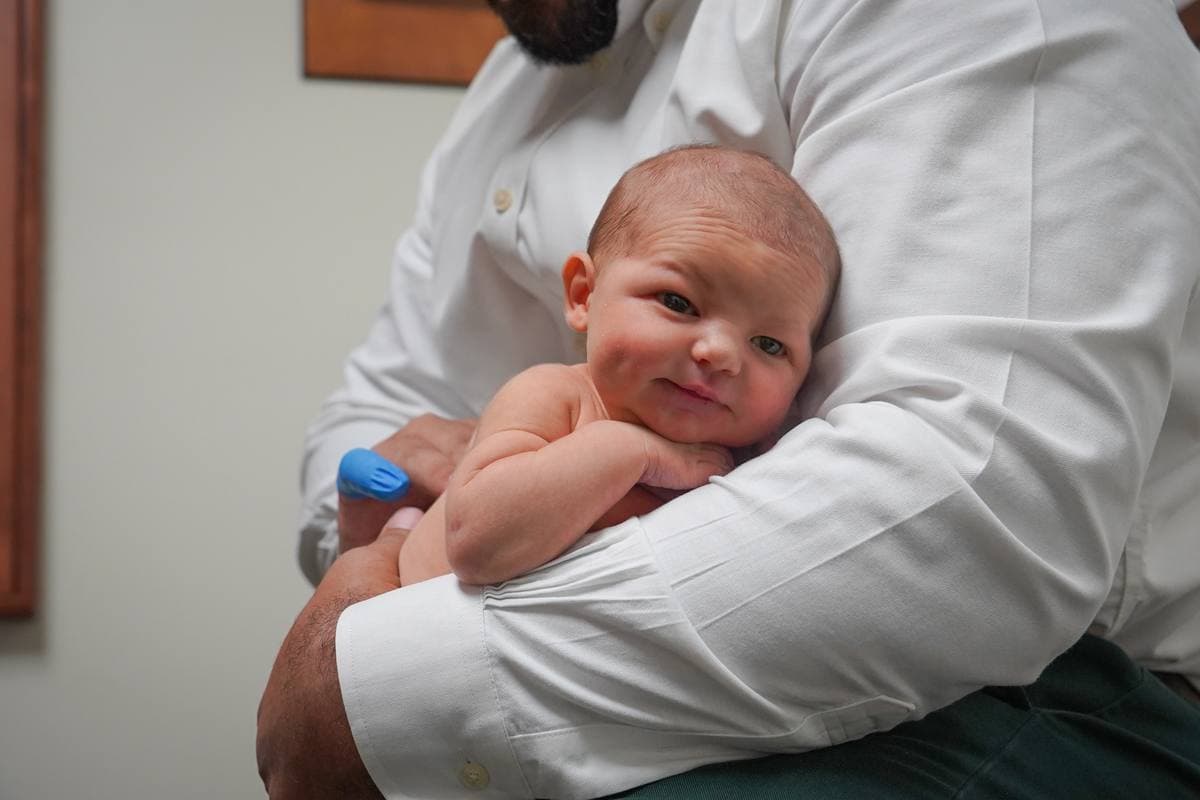Dr. Vin holding a peaceful newborn at Sláinte Chiropractic